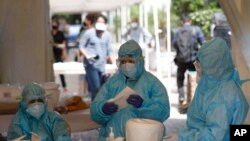 Health workers get ready at a COVID-19 testing center in New Delhi, India, April 27, 2020. India’s main medical research organization has cancelled orders to procure rapid antibody test kits from two Chinese companies. 