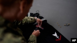 Chief Hospital Corpsman, United States Fleet Marine Forces, Jessica Zugzda attaches a ribbon rack to a dress Navy uniform in the uniform shop of the Air Force Mortuary Affairs Operations center at Dover Air Force Base, Del., July 9, 2021.