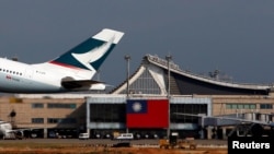 FILE - A Hong Kong Cathay Pacific Airways Airbus passenger plane takes off against the backdrop of a Taiwanese flag, at Taoyuan International Airport, Taiwan, Aug. 6, 2018.