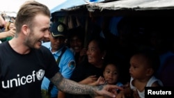 Former England soccer captain David Beckham greets victims of super Typhoon Haiyan at an evacuation center in Tacloban city in central Philippines February 13, 2014. Local officials said, Beckham is one of the biggest donors to super typhoon Haiyan devastated areas in central Philippines, February 13, 2014.