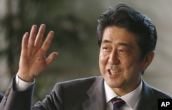 Japan's newly-named Prime Minsiter Shinzo Abe smiles as he waves at the media upon his arrival at the prime minister's official residence following his election at Parliament in Tokyo, December 26, 2012.