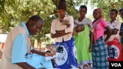 Un agent de santé enregistre les informations du passeport de santé du patient dans le district de Balaka, dans le sud du Malawi. (Lameck Masina / VOA)
