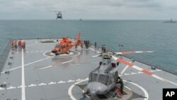 Sebuah helikopter mendarat di Kapal Induk Angkatan Laut RI KRI Banda Aceh, di pretorian dekat ditemukannya ekor pesawat AirAsia 8501 di Laut Jawa (8/1). Satu hari setelah tim SAR mengangkat ekor pesawat AirAsia yang jatuh di Laut Jawa, lagi-lagi suara sonar – atau biasa disebut sinyal ping – terdengar lagi hari Minggu (11/1). 