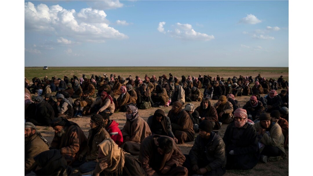 FILE - Men wait to be screened by U.S.-backed Syrian Democratic Forces (SDF) fighters after being evacuated out of the last territory held by Islamic State militants, near Baghuz, eastern Syria, Feb. 22, 2019.