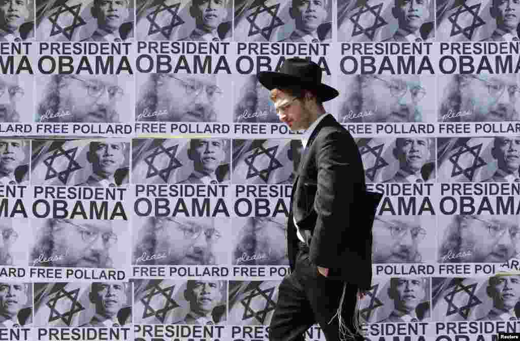 2013年3月20日，一位超正统派犹太教男士在耶路撒冷走过一个呼吁美国总统奥巴马释放乔纳森&middot;波拉德的标语。波拉德因为被判向以色列泄露美国机密而在1987年被判终身监禁，目前在美国监狱服刑。