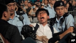 Pro-democracy activist Joshua Wong is detained by police officers after he climbed up to a giant flower statue bequeathed by Beijing in 1997 in Golden Bauhinia Square of Hong Kong, June 28, 2017.