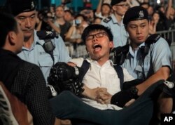 Pro-democracy activist Joshua Wong is detained by police officers after he climbed up to a giant flower statue bequeathed by Beijing in 1997 in Golden Bauhinia Square of Hong Kong, June 28, 2017.