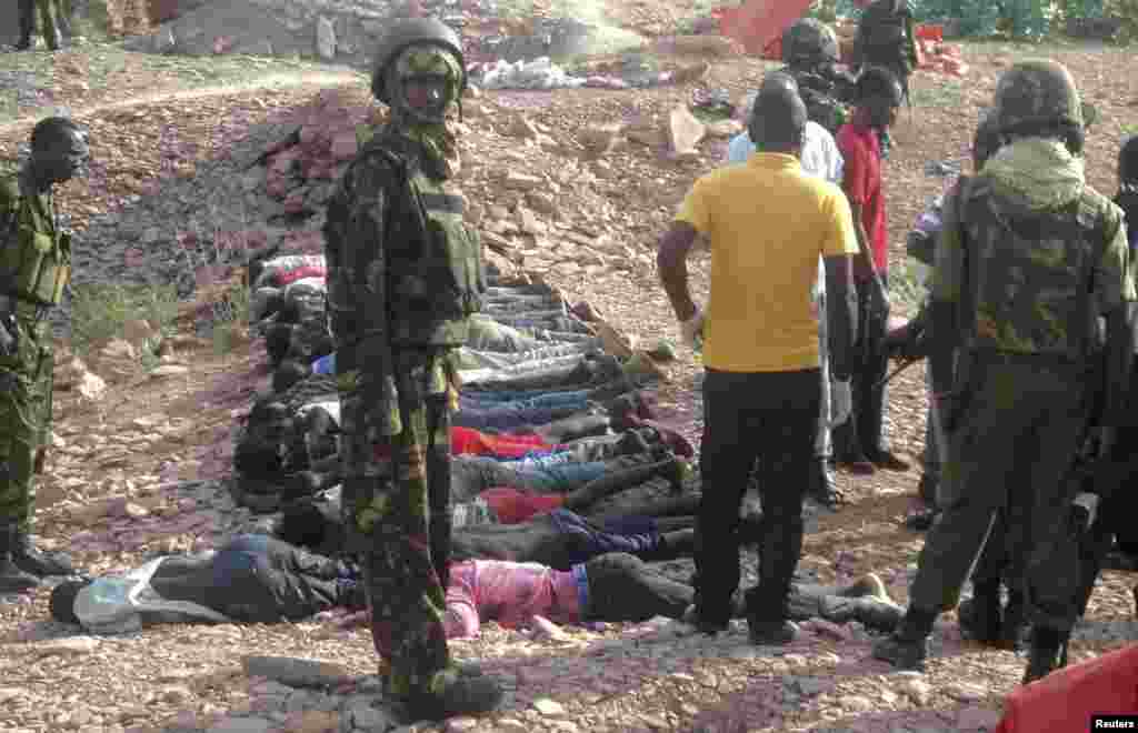 Kenyan military personnel stand near bodies lined up on the ground at a quarry site where attackers killed at least 36 workers in a village in Korome, outside the border town of Mandera, Dec. 2, 2014.