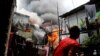 Seorang pria berusaha menyiramkan air ke arah rumahnya yang terbakar di kawasan permukiman informal Muntinlupa, Metro Manila, Filipina.