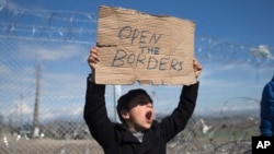 Kijana akishiriki katika mgomo uliofanywa na wakimbizi na wahamiaji mbele ya uzio wa waya unaotenganisha Ugiriki na Macedonia.