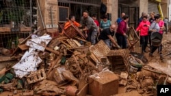 People clean mud from a shop affected by floods in Chiva, Spain, on Nov. 1, 2024.