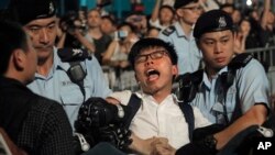 Aktivis pro-demokrasi Joshua Wong ditahan oleh petugas polisi setelah menaiki patung bunga raksasa yang diwariskan Beijing pada 1997 di Golden Bauhinia Square, Hong Kong, 28 Juni 2017.