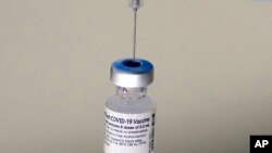 Se coloca una jeringa en un frasco de vacuna Pfizer-BioNTech en una clínica COVID-19 en Augusta, Maine, el martes 21 de diciembre de 2021.
