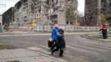 资料照片: 2022年11月4日乌克兰妇女们走过受损的公寓楼