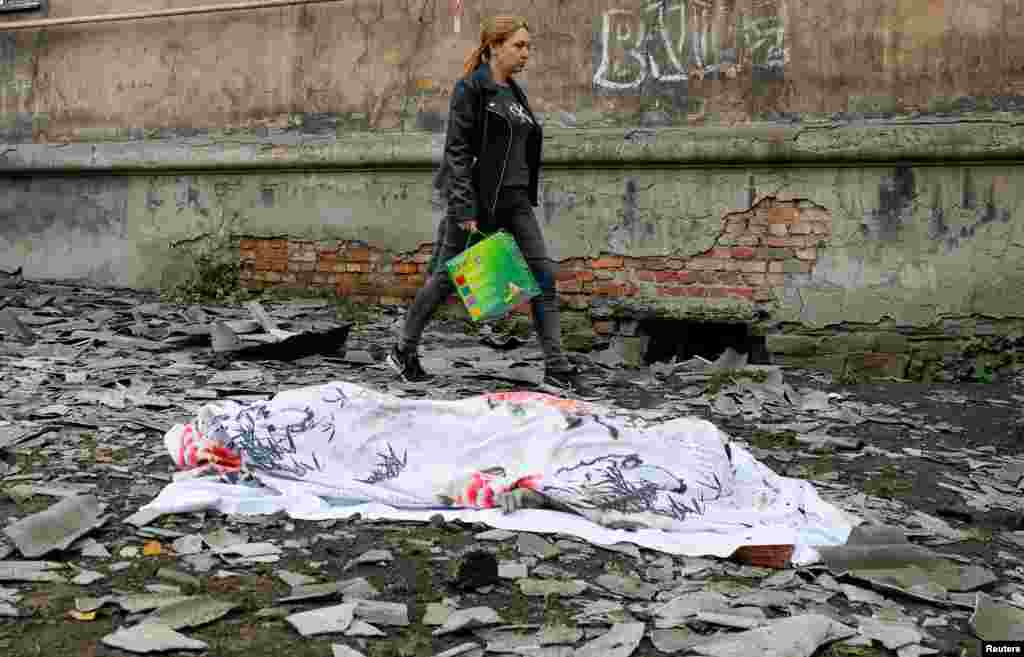 A local resident walks past the body of a person killed by recent shelling near a damaged block of flats in the course of Russia-Ukraine conflict in Makiivka, Russian-controlled Ukraine.