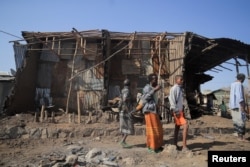 FILE - Residents and militias stand next to houses destroyed by an airstrike during the fight between the Ethiopian National Defence Forces and the Tigray People's Liberation Front (TPLF) forces in Kasagita town, Afar region, Ethiopia, Feb. 25, 2022.