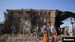 FILE - Residents and militia members stand next to houses destroyed by an airstrike during the fight between the Ethiopian National Defense Forces and the Tigray People's Liberation Front in Kasagita, Afar region, Ethiopia, Feb. 25, 2022.