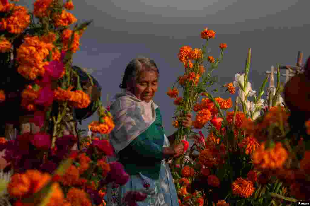 An indigenous woman decorates the grave of her loved one with Cempasuchil Marigolds at a cemetery during the annual Day of the Dead celebration, in San Miguel Canoa, in Puebla state, November 1, 2022.&nbsp;