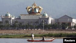 People maneuvre a small boat along the Mekong river in front of the Kings Roman casino opposite Sop Ruak in the Golden Triangle region where the borders of Thailand, Laos and Myanmar meet, Jan. 15, 2012.