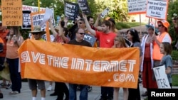 FILE - Pro-net neutrality activists rally in the neighborhood where President Barack Obama attended a fundraiser in Los Angeles, July 23, 2014.