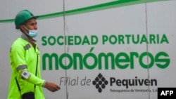 Un trabajador camina junto a un cartel de la empresa venezolana de fertilizantes Monómeros, en Barranquilla, Colombia, el 9 de octubre de 2021.