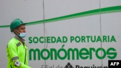 Un trabajador pasa junto a un cartel de la empresa venezolana de fertilizantes Monómeros, en Barranquilla, Colombia. Octubre 9, 2021.