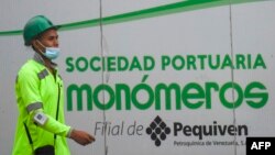 ARCHIVO - Un trabajador pasa junto a un cartel de la empresa venezolana de fertilizantes Monómeros, en Barranquilla, Colombia, el 9 de octubre de 2021.