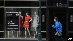 A jogger runs past Rococo, a clothing store, April 16, 2020, in Birmingham, Michigan. Due to funding shortages, the government's lending program for small businesses is on hold. 