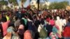 Sudanese demonstrators flash the victory sign as a military police vehicle drives past them during a protest demanding Sudanese President Omar Al-Bashir step down in Khartoum, Sudan, April 6, 2019. 