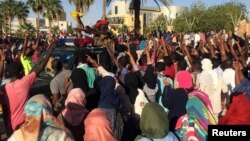 Sudanese demonstrators flash the victory sign as a military police vehicle drives past them during a protest demanding Sudanese President Omar Al-Bashir step down in Khartoum, Sudan, April 6, 2019. 