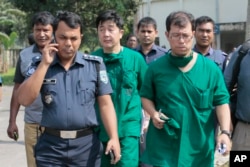 FILE - A Japanese doctor, front right, and the chief security officer of the Japanese embassy in Bangladesh, center, walk back from the morgue after the autopsy on the body of killed Japanese citizen Kunio Hoshi at Mahiganj village in Rangpur district.