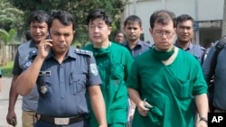 A Japanese doctor, front right, and the chief security officer of the Japanese embassy in Bangladesh, center, walk back from the morgue after the autopsy on the body of killed Japanese citizen Kunio Hoshi at Mahiganj village in Rangpur district, 300 kilom