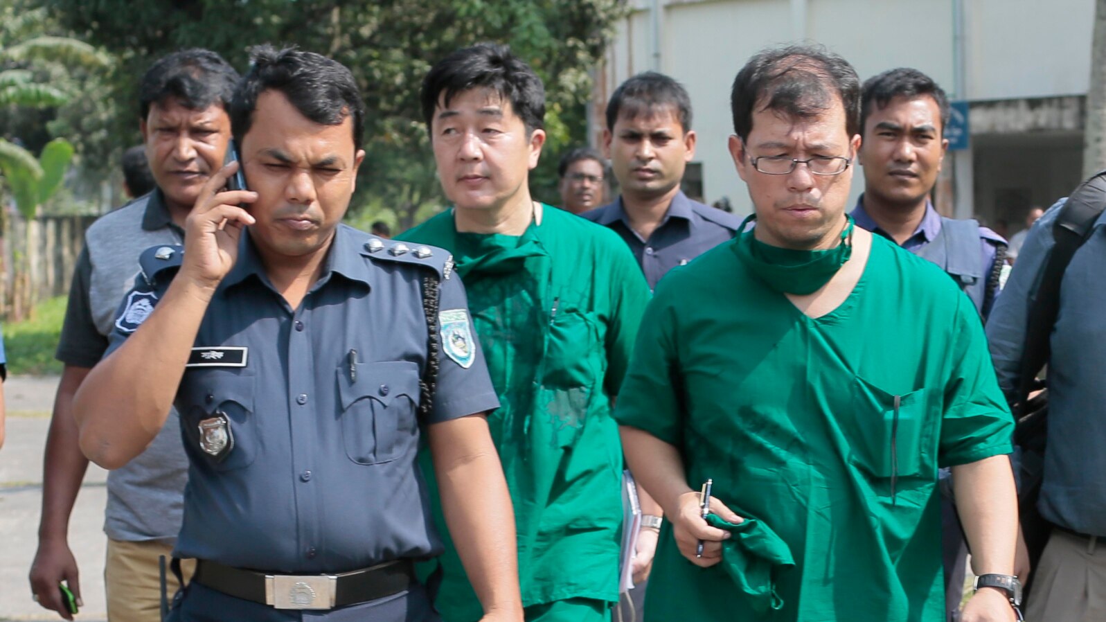 FILE - A Japanese doctor, front right, and the chief security officer of the Japanese Embassy in Bangladesh, center, walk back from the morgue after the autopsy on the body of Kunio Hoshi at Mahiganj village, 300 kilometers north of Dhaka, Oct. 4, 2015.