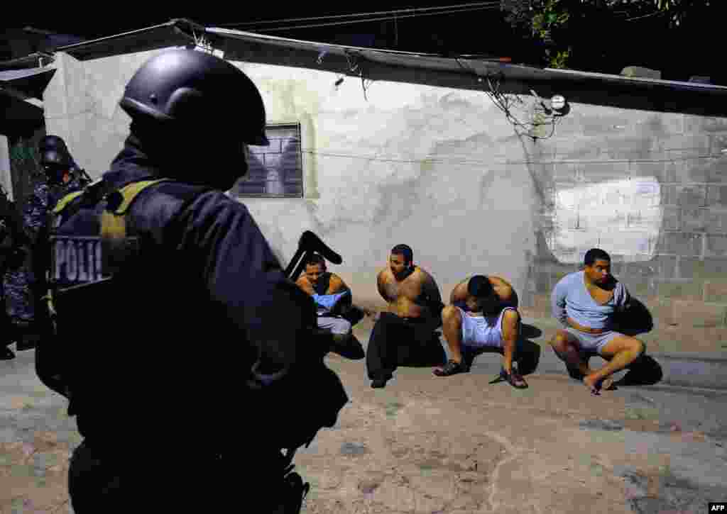 Un garde de la Police Nationale surveille des supposés membres du gang MS-13 pendant une opération à Santa Tecla, à l'est de San Salvador, le 31 janvier 2008.