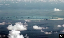 FILE - This photo taken through a window of a military plane shows China's apparent reclamation of Mischief Reef in the Spratly Islands in the South China Sea, May 11, 2015.