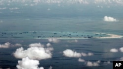 FILE - This photo taken through a window of a military plane shows China's apparent reclamation of Mischief Reef in the Spratly Islands in the South China Sea, May 11, 2015.