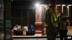 People believed to be migrants are stopped by police outside the Manston immigration short-term holding facility in Kent, England, Nov. 2, 2022.