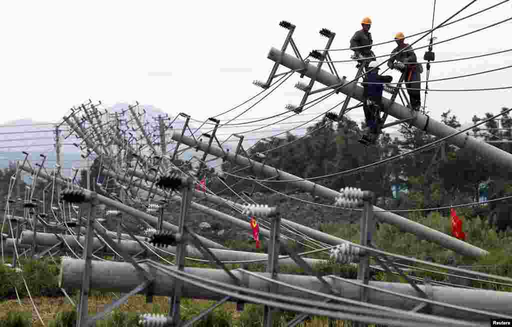 Laborers work to reconnect an electric circuit after pylons were turned over by Typhoon Haikui in Wenling, Zhejiang province, China, August 8, 2012. 