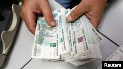 Seorang karyawan di sebuah perusahaan swasta di Krasnoyarsk, Siberia, menghitung pecahan uang kertas mata uang Rusia, rubel (foto: dok).