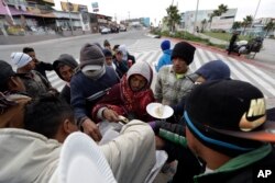 A volunteer hands out tacos to a group of migrants from Central America in Tijuana, Mexico, Nov. 14, 2018.