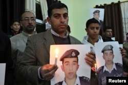 Jawdat Safi, brother of Islamic State captive Jordanian pilot Muath al-Kaseasbeh, holds a lit candle along with a poster of his brother as he takes part in a rally in support of al-Kaseasbeh at the family's headquarters in the city of Karak, Jan. 31, 2015