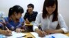 Student Pham Thi Trang (right) studies Japanese at a free language school set up by a street vendor, Hanoi, Vietnam, Aug. 7, 2014. (Marianne Brown/VOA)