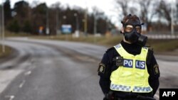 A police officer wearing a gas mask stands guard at the scene after emergency services were alerted to Sweden's Security Service headquarters in Solna, north of Stockholm, because of a suspected gas leak on Feb. 23, 2024.