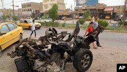 Civilians pass a destroyed car in the a car bomb explosion in southwestern Baghdad, Iraq, May 20, 2017.