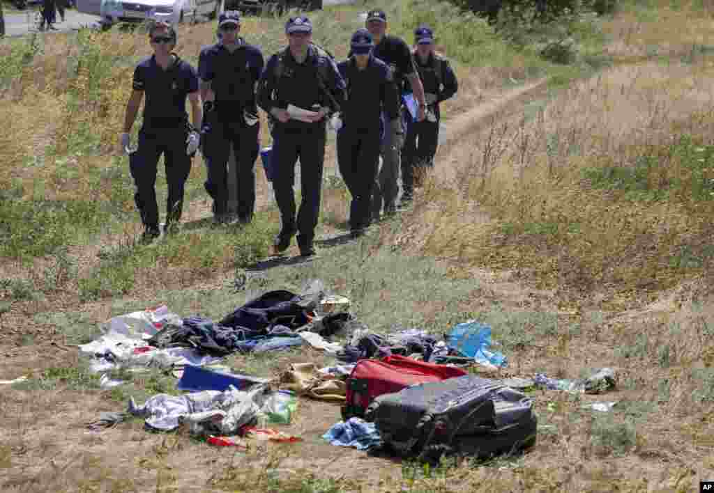 Australian investigators examine the area of the Malaysia Airlines MH17 plane crash in the village of Hrabove, Donetsk region, eastern Ukraine, Aug. 1, 2014. 