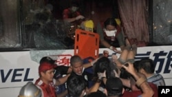 A paramedic (top) lowers one of the wounded survivor from the hijacked bus in Manila, 23 Aug 2010