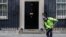 A workman sweeps up leaves in front of 10 Downing Street in London, Oct. 30, 2019. 