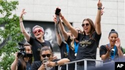 Integrantes del equipo femenino de fútbol de EE.UU. incluyendo Megan Rapinoe, (al fondo a la izquierda), y Alex Morgan, (en el fondo a la derecha) se desplazan en una carroza durante un desfile en la ciudad de Nueva York el miércoles, 10 de julio de 2019.