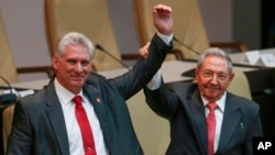 Cuba's outgoing President Raul Castro, right, and new President Miguel Diaz-Canel raise their arms in unison at the National Assembly in Havana, Cuba, April 19, 2018. 