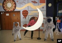An employee playfully hugs a cutout of a crescent moon at the Nehru Planetarium in New Delhi, India, July 11, 2019. India is preparing its second unmanned mission to the moon, this one aimed at landing a rover near the unexplored south pole.